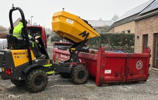 évcuation déchets avec mini-pelle dans un container rouge