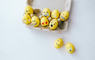 oeufs peints en jaunes avec visages smileys dans une boîte