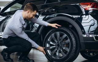 homme controlant ses pneus de voiture