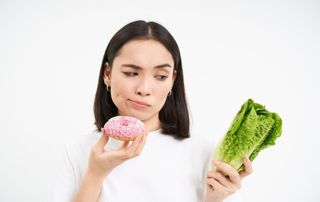 femme hésitant entre un légume et un donut