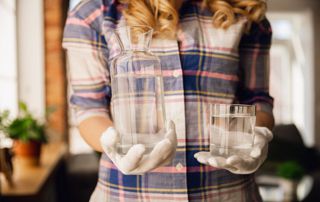 femme tenant un verre d'eau et une carafe