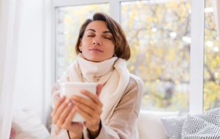 femme assise se réchauffant avec une boisson chaude