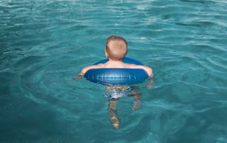 Enfant de dos dans une bouée, flottant dans une piscine